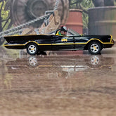Model of a black Batmobile on a wooden surface with a blurred background